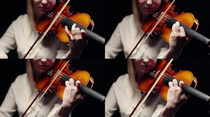 女小提琴手在工作室用琴弓和手指弹奏小提琴，背景很暗。交响乐团