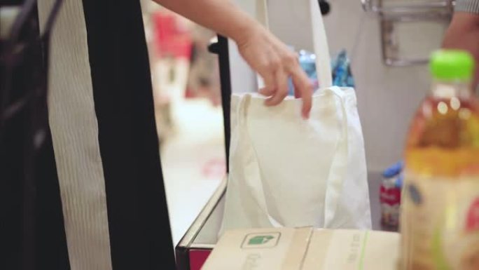 亚洲年轻女子在超市用可重复使用的布购物