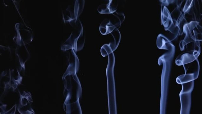 白烟以慢动作漂浮在黑色背景上的太空中。烟雾喷射形成复杂的抽象图案。特写