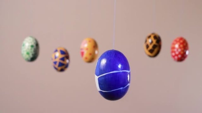 带有蒙面的蓝色鸡蛋在浅米色背景上与其他复活节彩蛋的背景下旋转。大流行冠状病毒和复活节假期的概念。