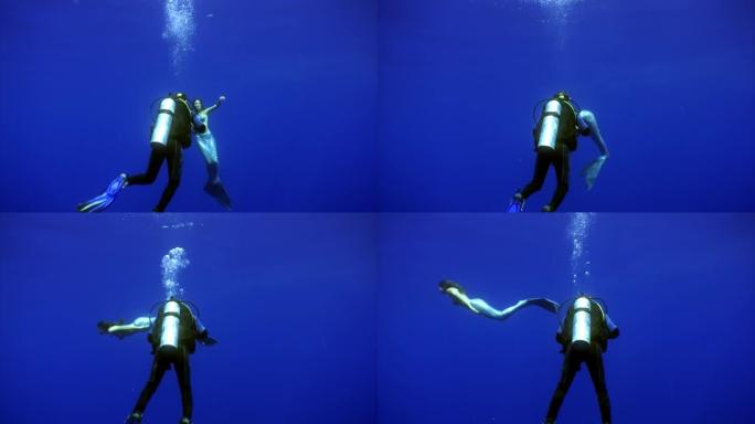 年轻的美人鱼为海上水下摄影师的相机摆姿势。