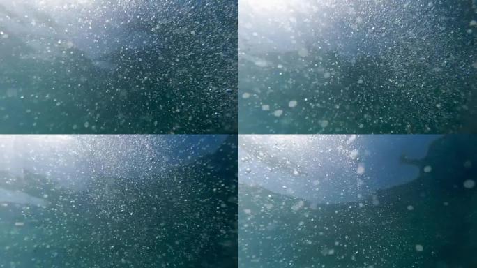 从海底看，许多气泡在太阳光线下漂浮到海面上
