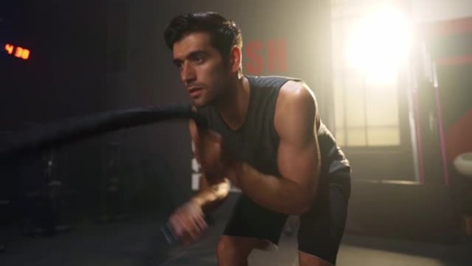 男子训练进行搏斗绳索锻炼，锻炼手臂和有氧运动。健身人士在健身房用战斗绳锻炼。