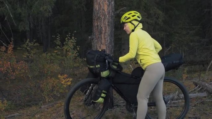 这位女士乘坐混合地形自行车旅行，骑自行车旅行。旅行者带着自行车包旅行。魔法森林公园。