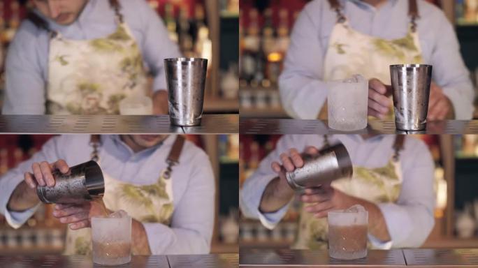 酒保将鸡尾酒倒入冰霜玻璃中的镜头。