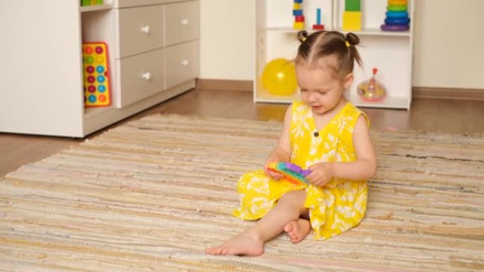 一个小女孩正拿着流行玩具在儿童房里玩耍。一个令人着迷的感官玩具。