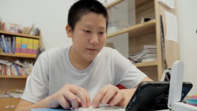 亚洲男孩在家通过智能手机和无线键盘玩网络游戏，生活方式概念。
