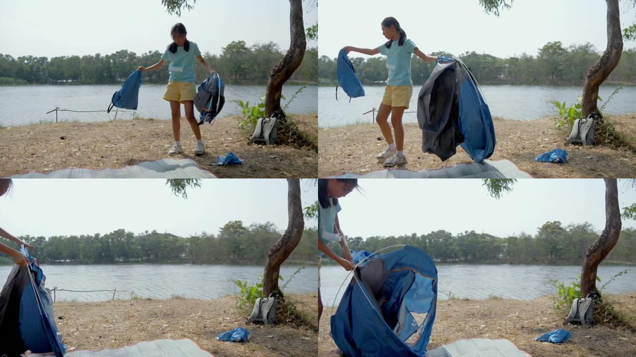 亚洲女孩试图在户外湖附近的地面上搭帐篷，生活方式概念。