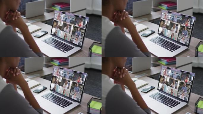 非裔美国妇女的中部与办公室的同事在笔记本电脑上进行视频会议
