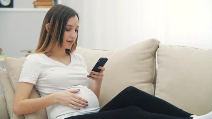 4k慢动作孕妇微笑发短信的视频。