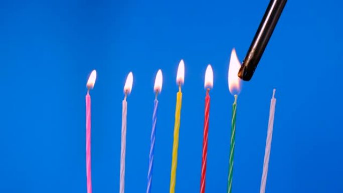 一组在蓝色背景下明亮燃烧的生日蜡烛。
