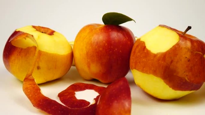 成熟的新鲜苹果，切片和苹果皮躺在白色桌子上