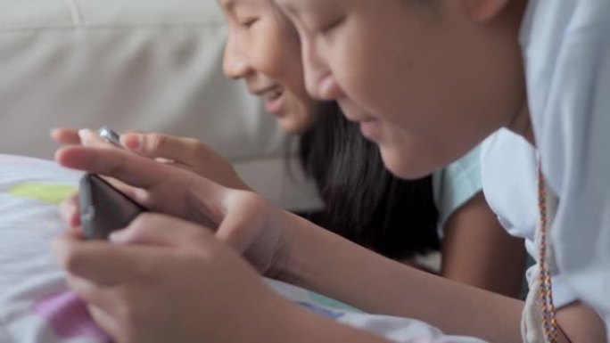 快乐的亚洲儿童在家里一起在地板上玩网络游戏，生活方式理念。