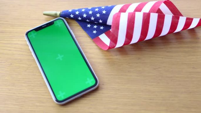 美国国旗躺在桌子上与手机色度键模拟屏幕