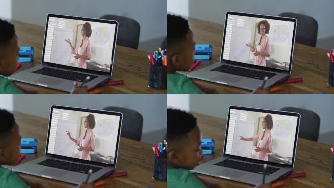 非裔美国男孩坐在桌子上使用笔记本电脑上在线课程