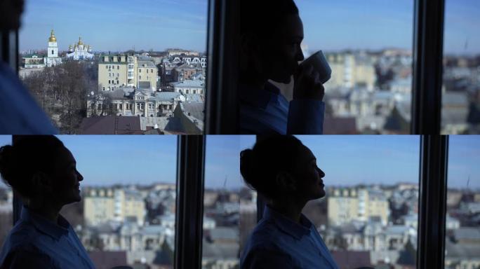 女人在酒店窗口观察到的风景优美的城市景观