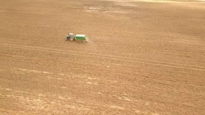 农用拖拉机喷洒肥料的鸟瞰图。