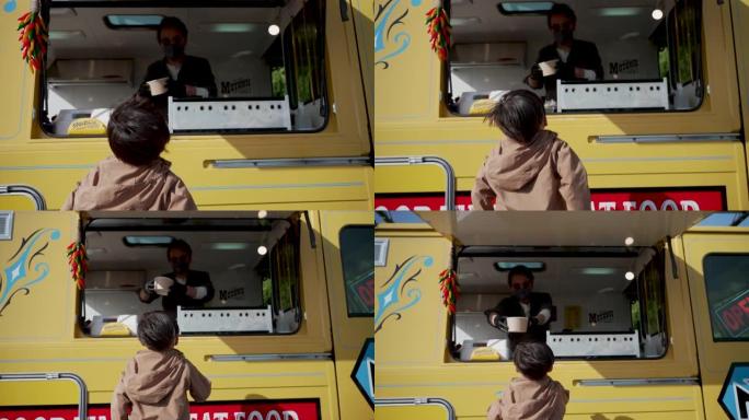 一个小男孩从食品卡车上买午餐的中等镜头