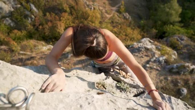 一名年轻女子在岩石山上攀爬的高角度视图