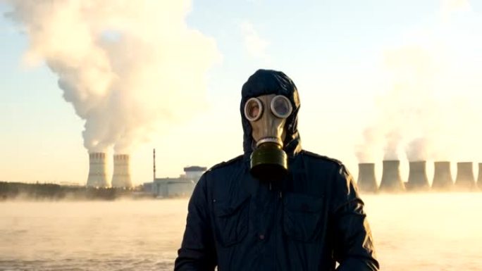 核电站冷却塔的延时发电厂将化学物质释放到大气中。一个人戴着防毒面具站着。储液罐蒸发了。全球变暖和辐射