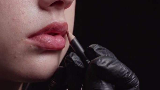 化妆师在模特嘴唇上涂抹唇笔。