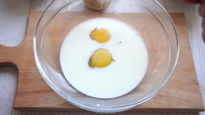 在家烹饪糕点过程。在装有牛奶和鸡蛋的碗中加入糖并混合。