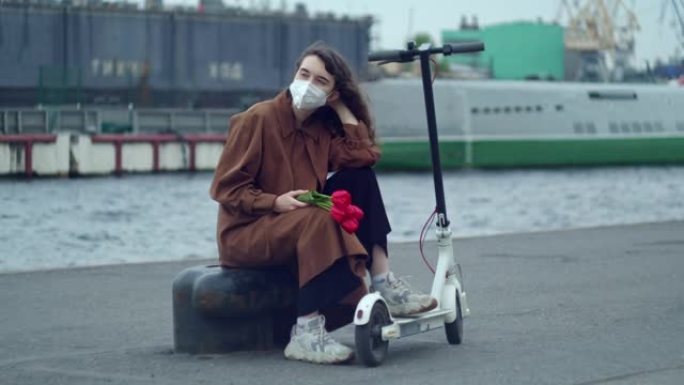 一个戴着防护面具，戴着红花的女人，郁金香在情人的码头上等着，旁边站着一辆踏板车