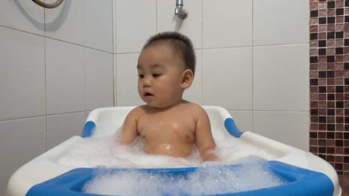 小孩子有趣的在家里的浴室内部用肥皂泡洗澡