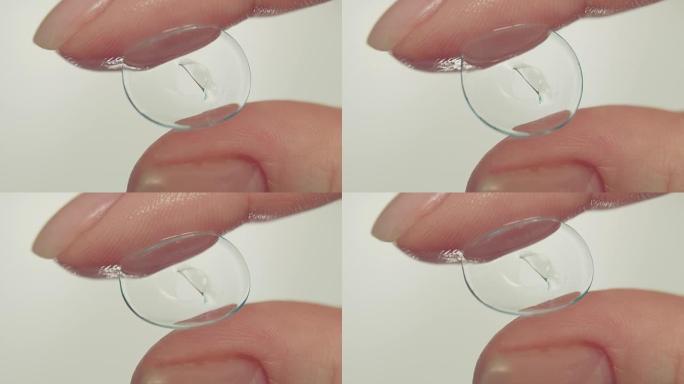 女性手指拿着受损的软性隐形眼镜，特写