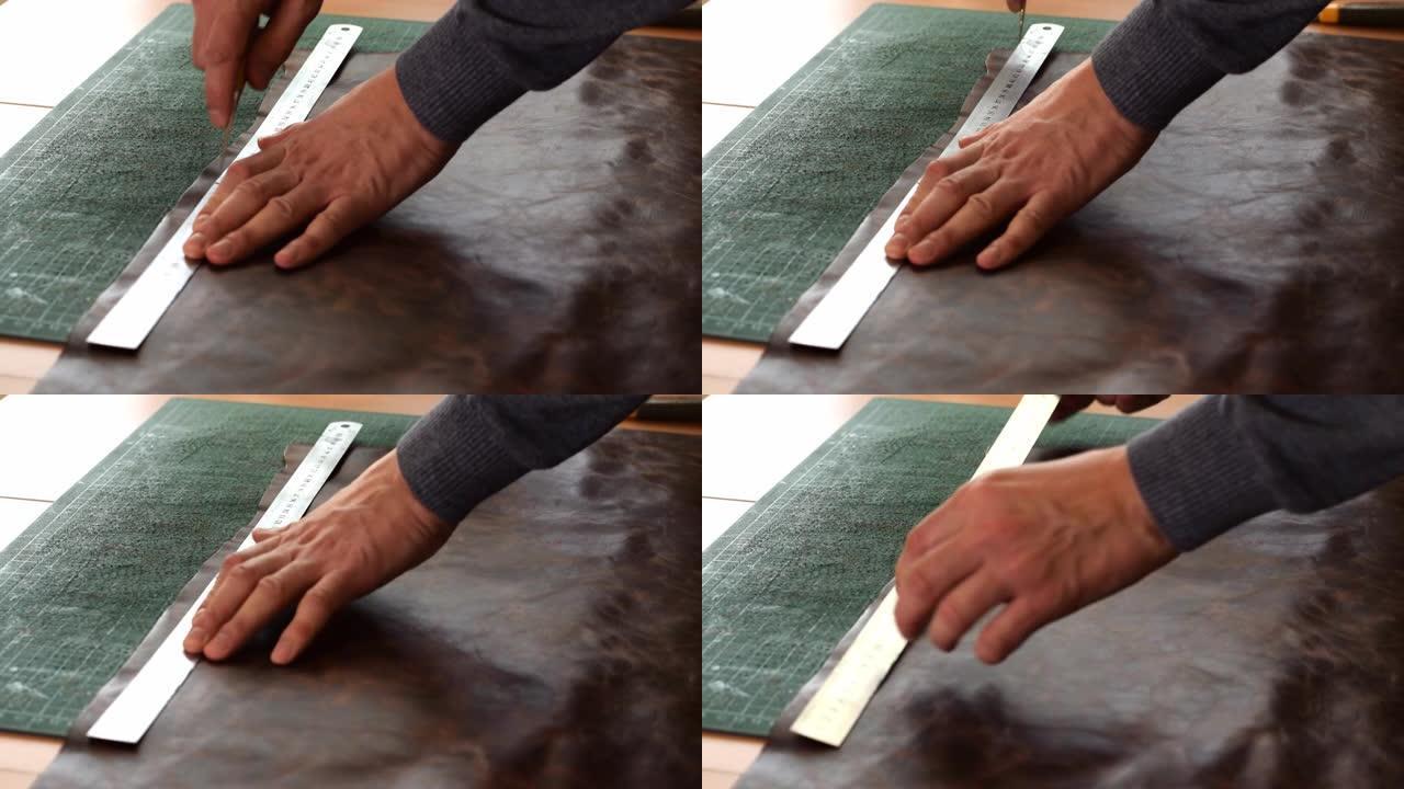 工匠用尺子和锥子在棕色皮革上做标记。手工皮革制造商。