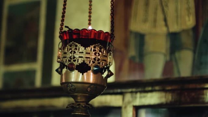 在教堂的铁链上悬挂着一个碗，里面装有燃烧的蜡烛。在特写镜头中拍摄宗教物品