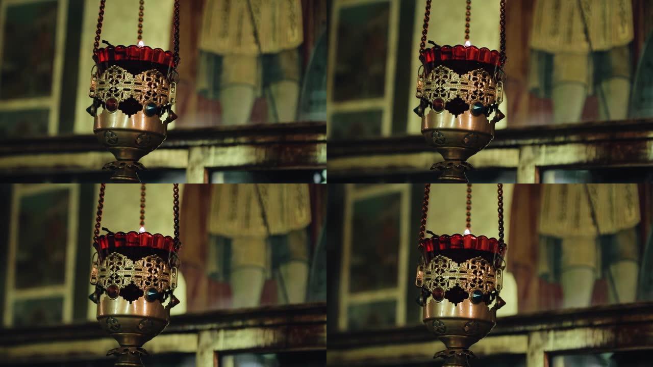 在教堂的铁链上悬挂着一个碗，里面装有燃烧的蜡烛。在特写镜头中拍摄宗教物品