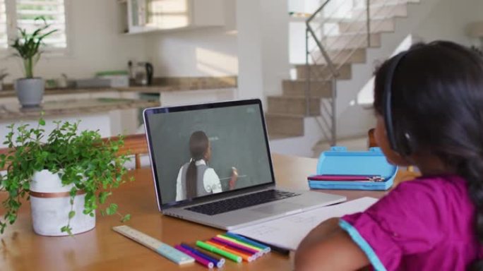 混血女孩坐在桌子上使用笔记本电脑上在线学校课程