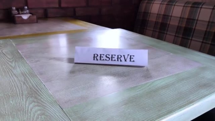 保留了盘子周围的飞行，盘子立在餐厅的木桌上。在咖啡馆预订一个地方。座位预订。提前在机构预订一张桌子。