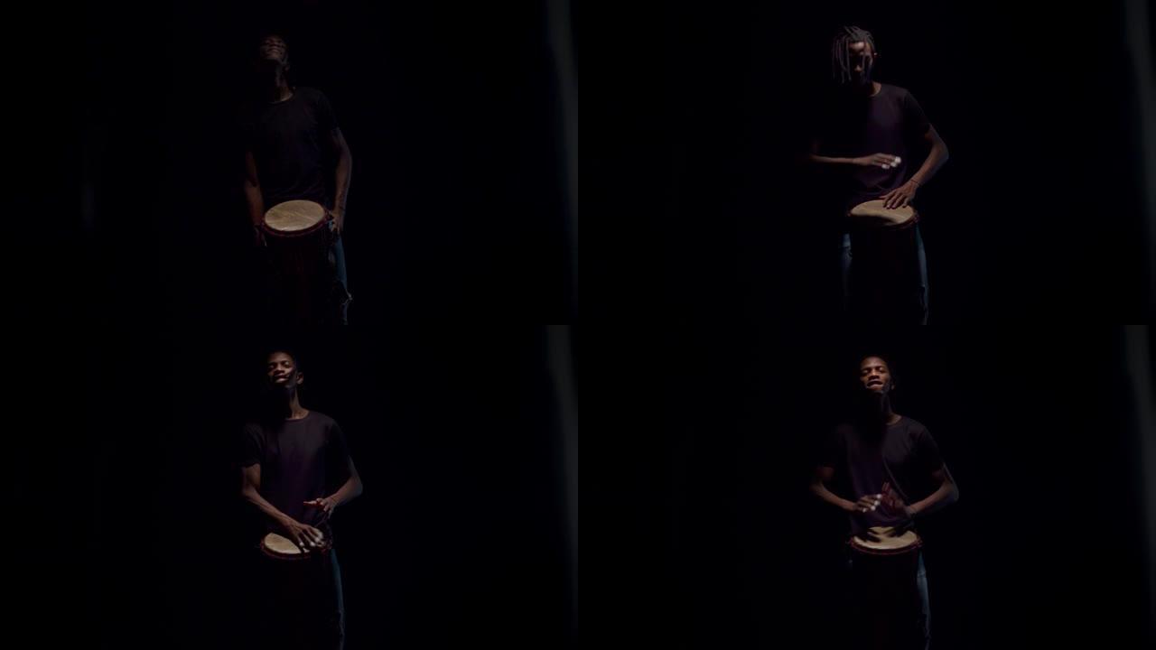 来自黑暗的黑人鼓手微笑着在非洲鼓上演奏。快乐的音乐家打鼓，黑色背景。音乐和艺术的概念
