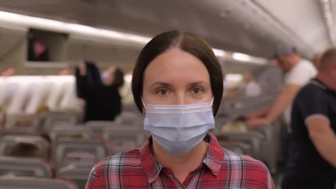 旅行者旅游女子戴着口罩坐飞机看相机。病毒疫情。冠状病毒新型冠状病毒肺炎检疫旅客旅行大流行概念。旅游航
