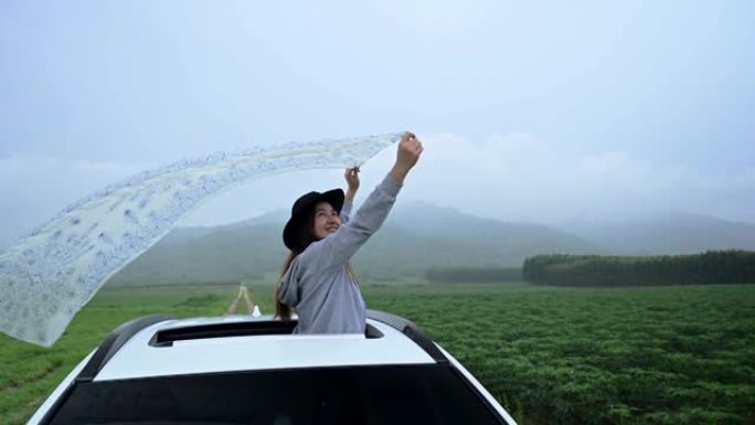 站在汽车天窗外面的亚洲女人。春天放松和自由。年轻游客暑假独自在泰国旅行。