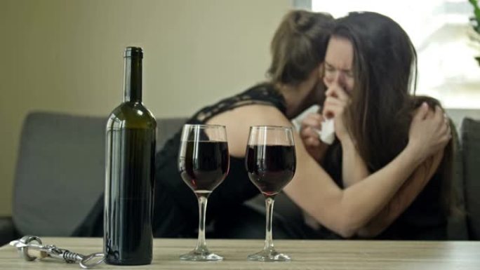两个女朋友正在喝酒。一个女人哭了，另一个安慰她。试图用酒精缓解压力