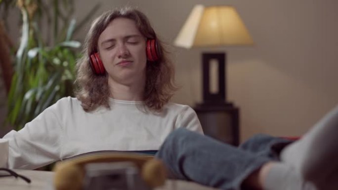 戴着耳机的快乐放松的年轻人的肖像，闭着眼睛听着模仿吉他演奏的音乐。无忧无虑的高加索20世纪80年代2