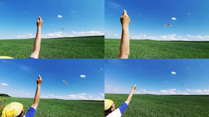 从麦田的角度来看，手在湛蓝的天空中放风筝。童年的乐趣。