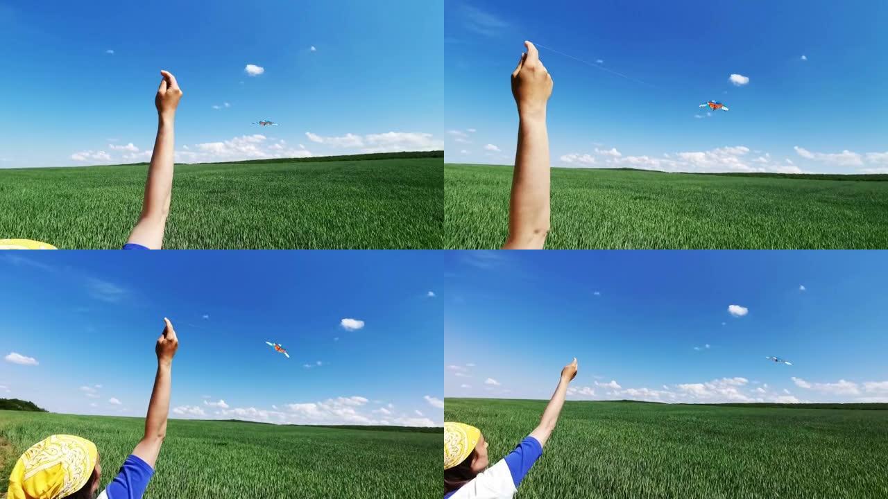 从麦田的角度来看，手在湛蓝的天空中放风筝。童年的乐趣。