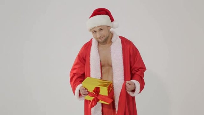 圣诞节。性感的圣诞老人。年轻的肌肉男戴着圣诞老人的帽子，拿着圣诞老人的袋子