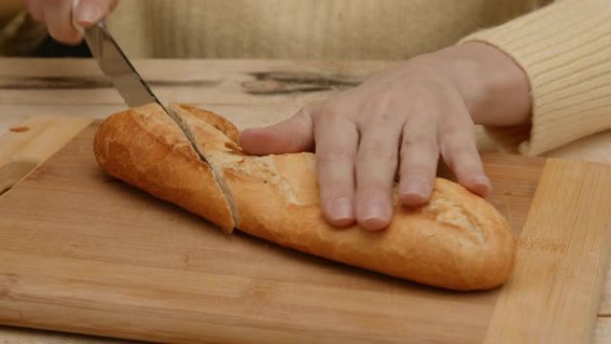 女人用刀切硬皮面包或法棍面包