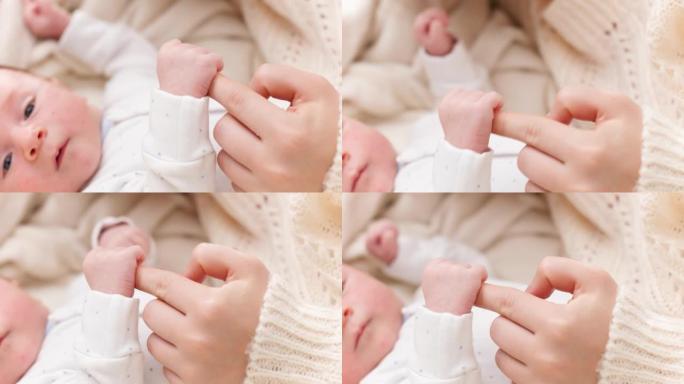 新生男婴用小手握住和抓住母亲的手指的特写镜头。家庭幸福与有小孩的父母的观念