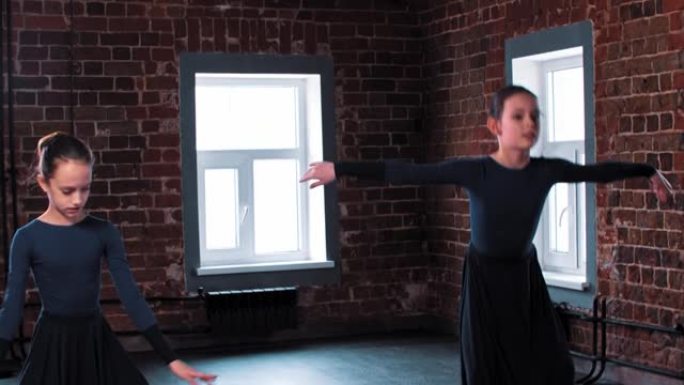 两个芭蕾舞女演员在工作室训练中穿着深色长裙跳舞