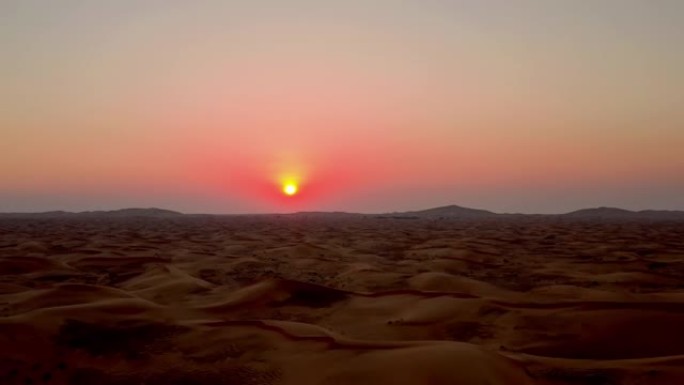 沙漠中的日落。天空似乎着火了。波浪形式的沙子无处不在。