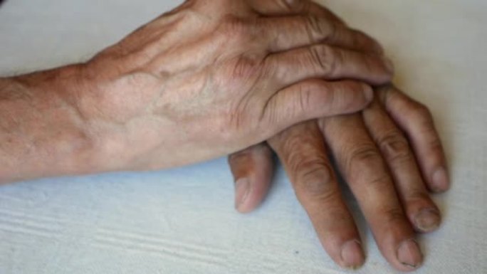 一个白人老人皱纹的手的特写。养老金领取者的手互相抚摸。人的手。选择性聚焦，浅景深
