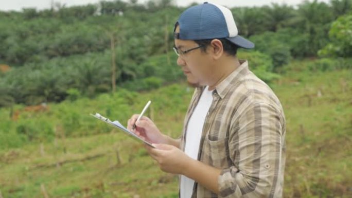 亚洲人环境学家在自然中做工作，使他的研究的书面文件