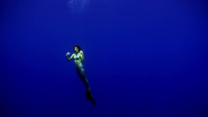 美人鱼女孩水下模型在大海干净的蓝色背景上跳舞。