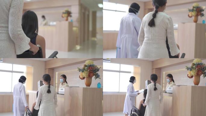 在医院大厅里，年轻夫妇的病人与接待员交谈